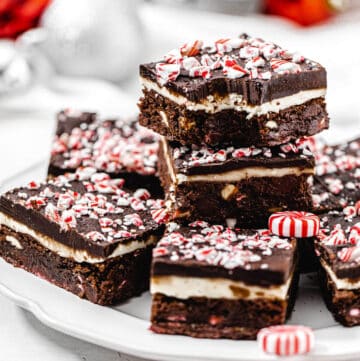 brownies stacked on a white plate with bite taken out of top brownie