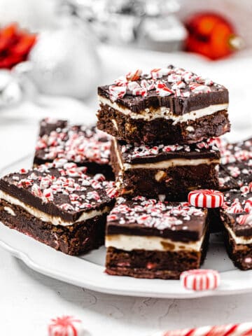 brownies stacked on a white plate with bite taken out of top brownie