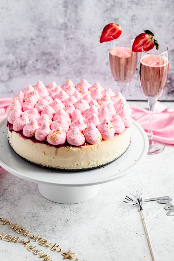 strawberry and champagne cake flavoured cheesecake on a white cake stand