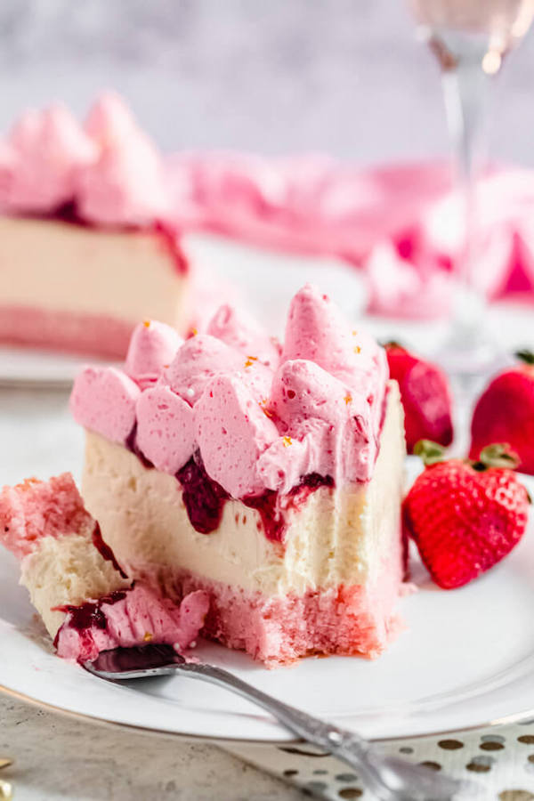 half eaten slice of cheesecake on a white plate with a strawberry on the side