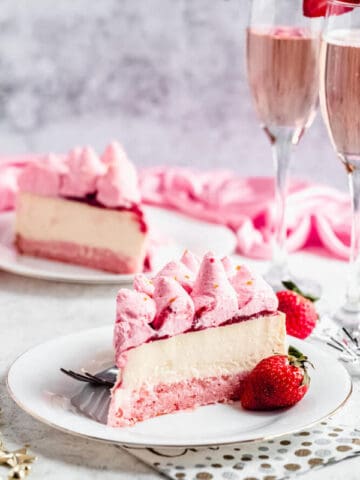 slice of champagne cheesecake on a white plate with a strawberry on the side