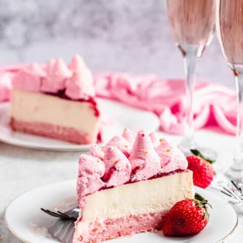 slice of champagne cheesecake on a white plate with a strawberry on the side