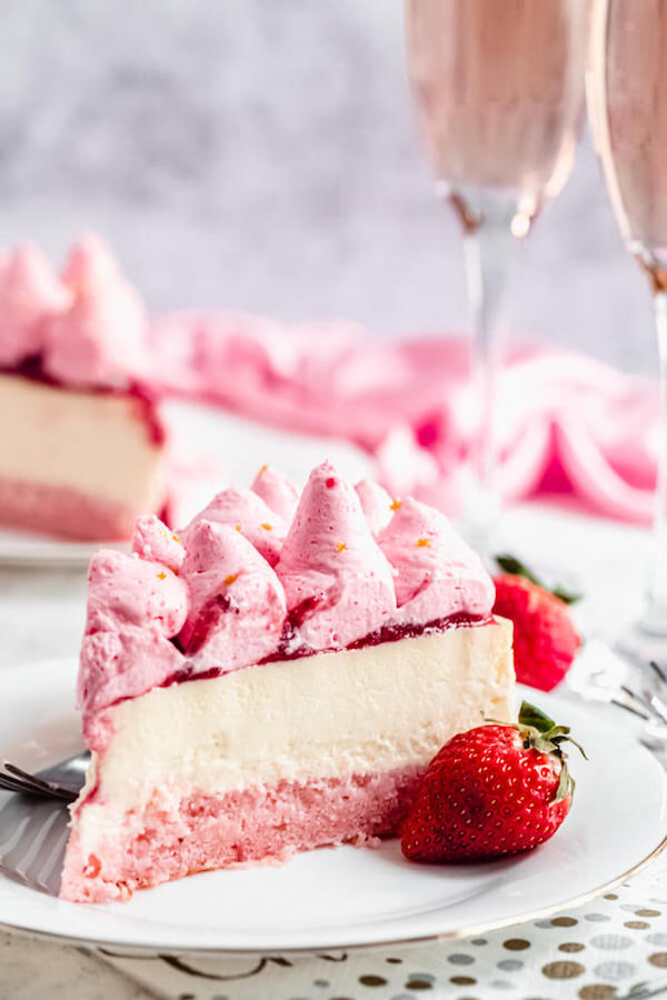 slice of pink and white champagne strawberry cheesecake on a white plate