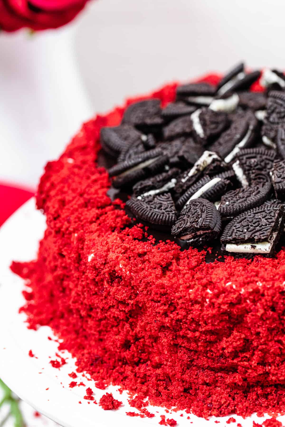 close up of cheesecake covered in red velvet cake crumbs and topped with chopped Oreos