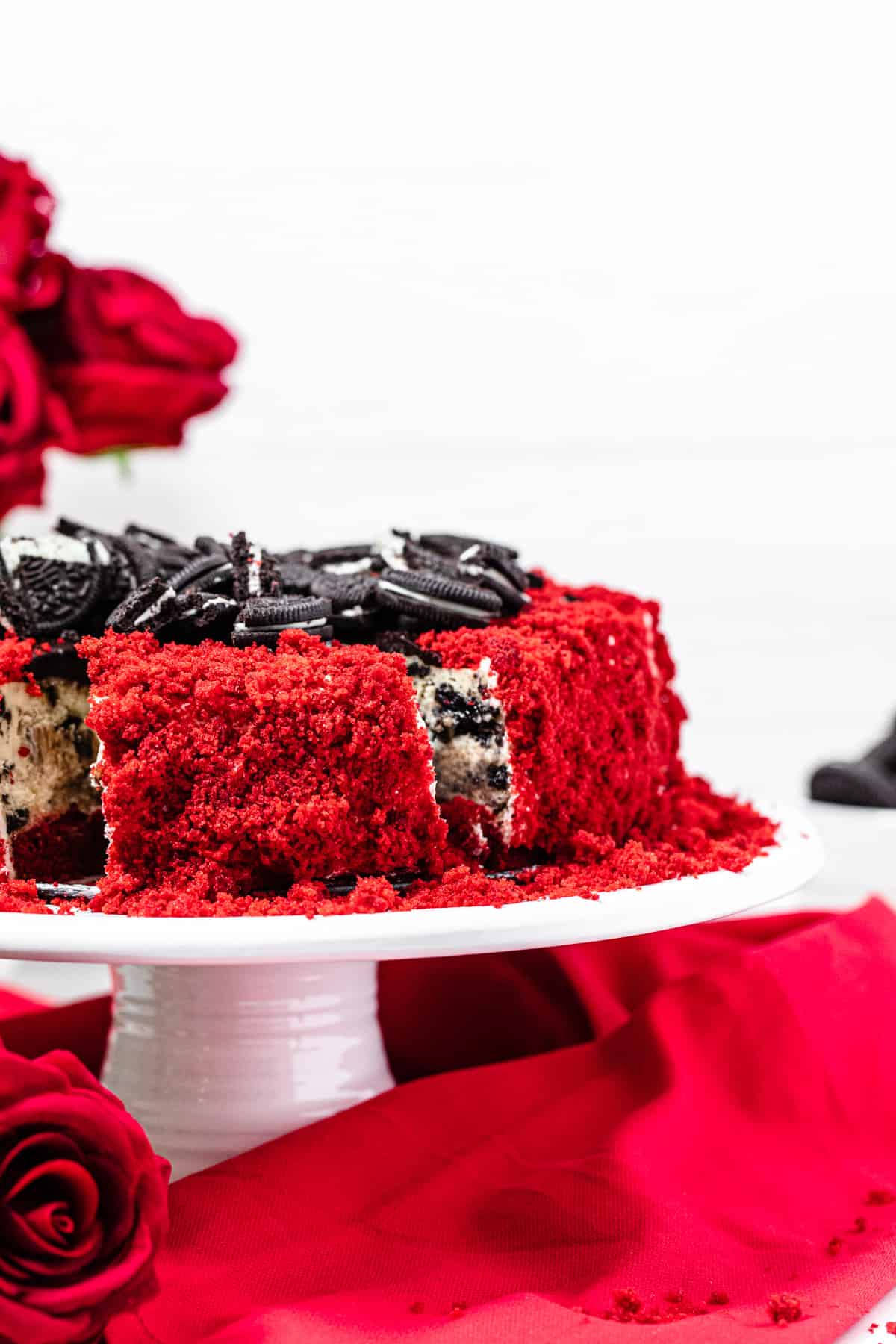 sliced cheesecake on a white cake stand with red napkin around the bottom