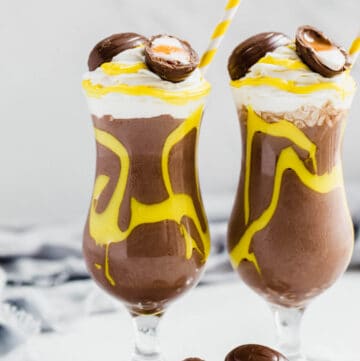two glasses of milkshake topped with Cadbury creme eggs