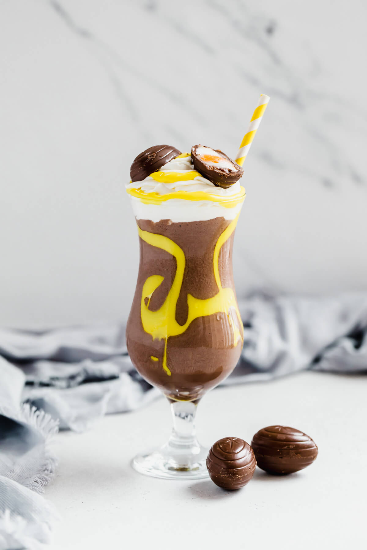 one glass of creme egg flavoured milkshake with two creme egg chocolates on the side