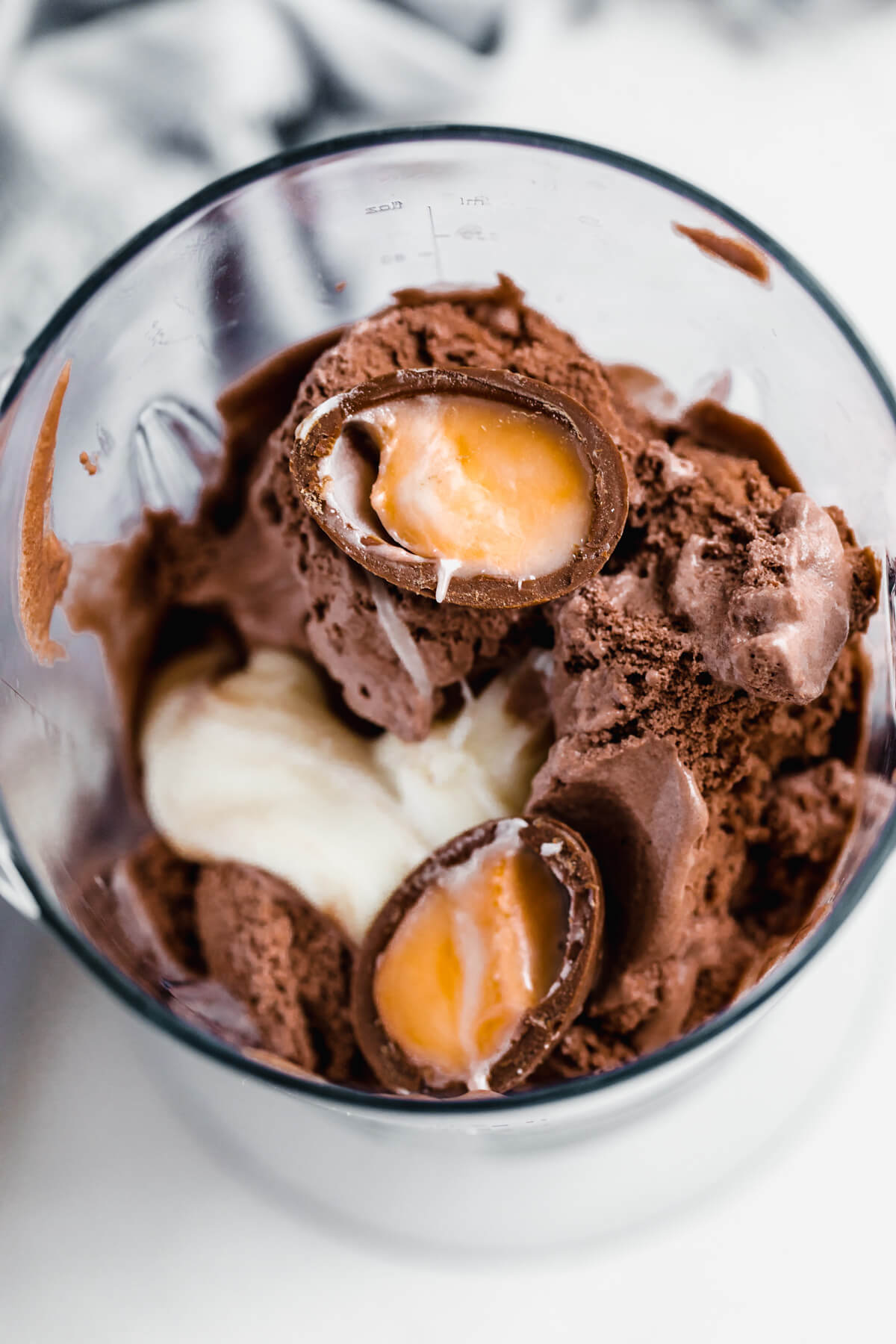 chocolate ice cream, homemade creme egg filling and a halved Cadbury creme egg in a blender