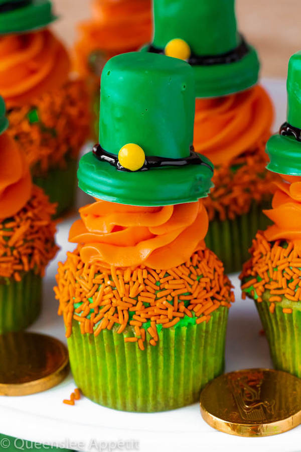 These Leprechaun Hat Cupcakes are super adorable and fun to make! A moist green vanilla cupcake stuffed with gold sprinkles, topped with a fluffy green and orange vanilla frosting and a cute little leprechaun hat sitting on top! This is the ultimate St. Patrick’s Day treat!