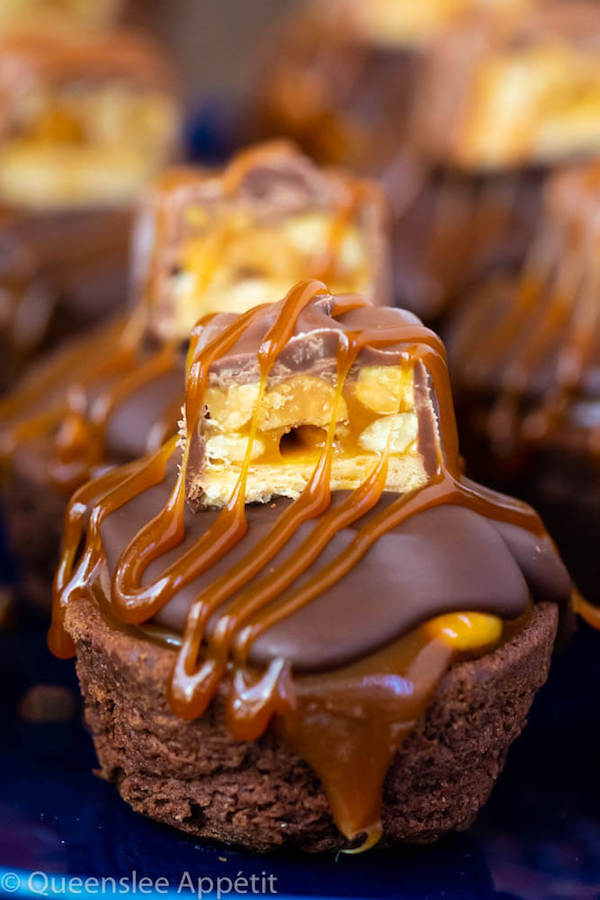 These Snickers Brownie Bites are made with pre-made brownie bites that are topped with a homemade peanut caramel sauce, chocolate peanut butter topping, a fun-size snickers bar and a drizzle of more salted caramel sauce! Such a simple and delicious bite sized treat!