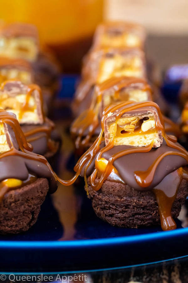 These Snickers Brownie Bites are made with pre-made brownie bites that are topped with a homemade peanut caramel sauce, chocolate peanut butter topping, a fun-size snickers bar and a drizzle of more salted caramel sauce! Such a simple and delicious bite sized treat!