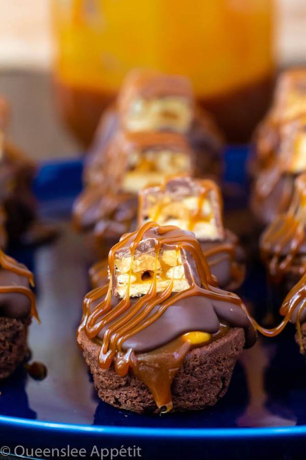 These Snickers Brownie Bites are made with pre-made brownie bites that are topped with a homemade peanut caramel sauce, chocolate peanut butter topping, a fun-size snickers bar and a drizzle of more salted caramel sauce! Such a simple and delicious bite sized treat!