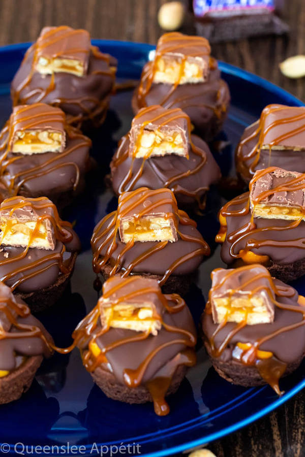 These Snickers Brownie Bites are made with pre-made brownie bites that are topped with a homemade peanut caramel sauce, chocolate peanut butter topping, a fun-size snickers bar and a drizzle of more salted caramel sauce! Such a simple and delicious bite sized treat!