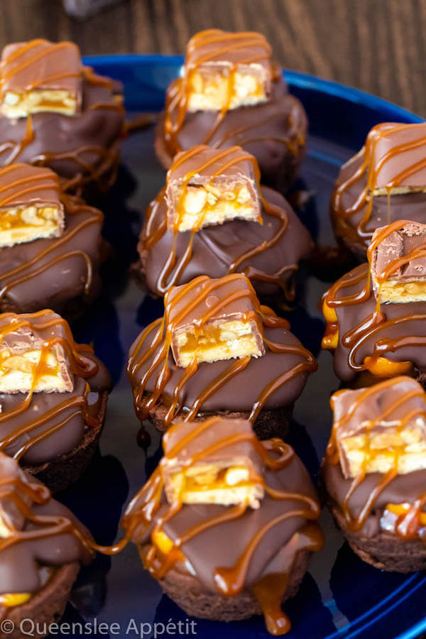 These Snickers Brownie Bites are made with pre-made brownie bites that are topped with a homemade peanut caramel sauce, chocolate peanut butter topping, a fun-size snickers bar and a drizzle of more salted caramel sauce! Such a simple and delicious bite sized treat!