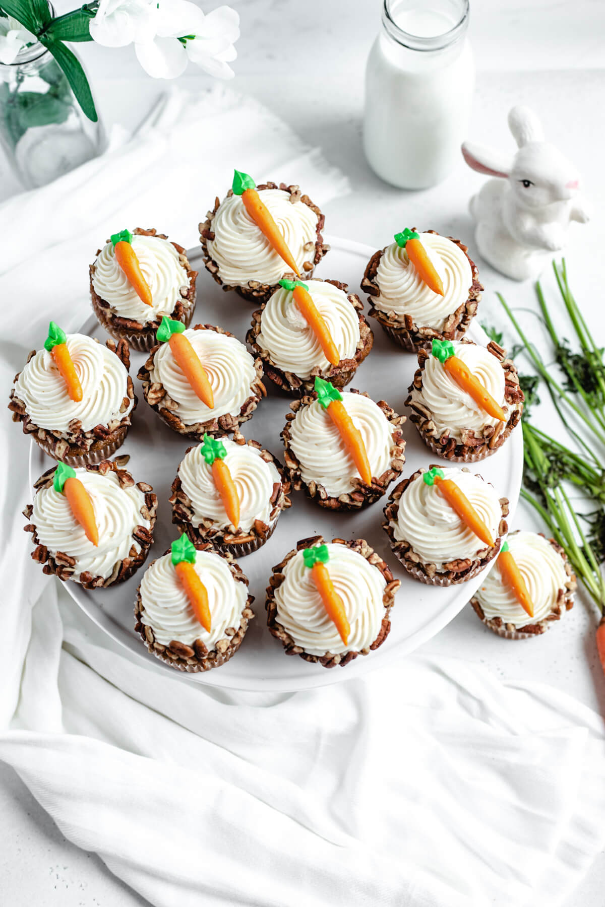 top of cupcakes on a cake stand with cream cheese carrots on top