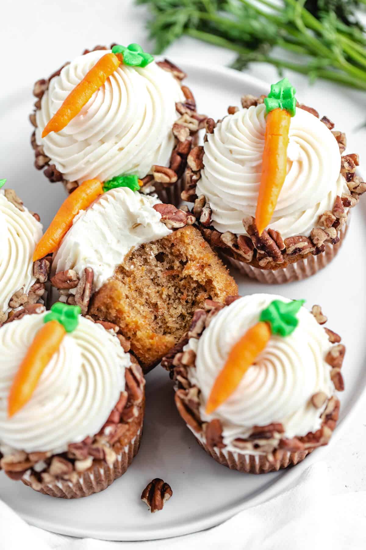 top of cupcakes on a white plate with a half eaten cupcake facing upwards in the middle 