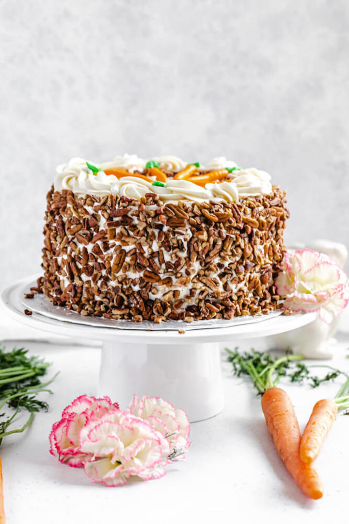 cake on a cake stand with carrots on the side