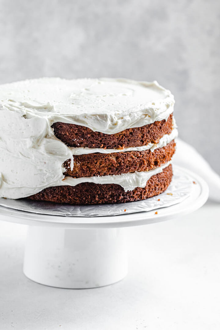 half frosted cake on a cake stand