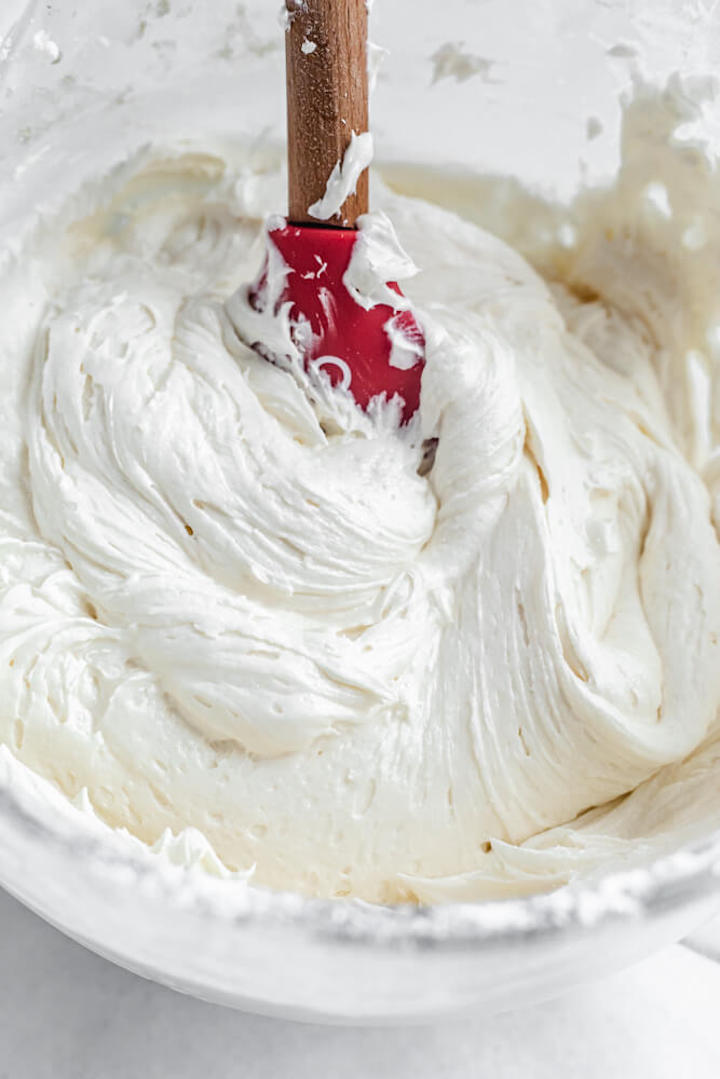 cream cheese frosting in a glass bowl with a spatula inside