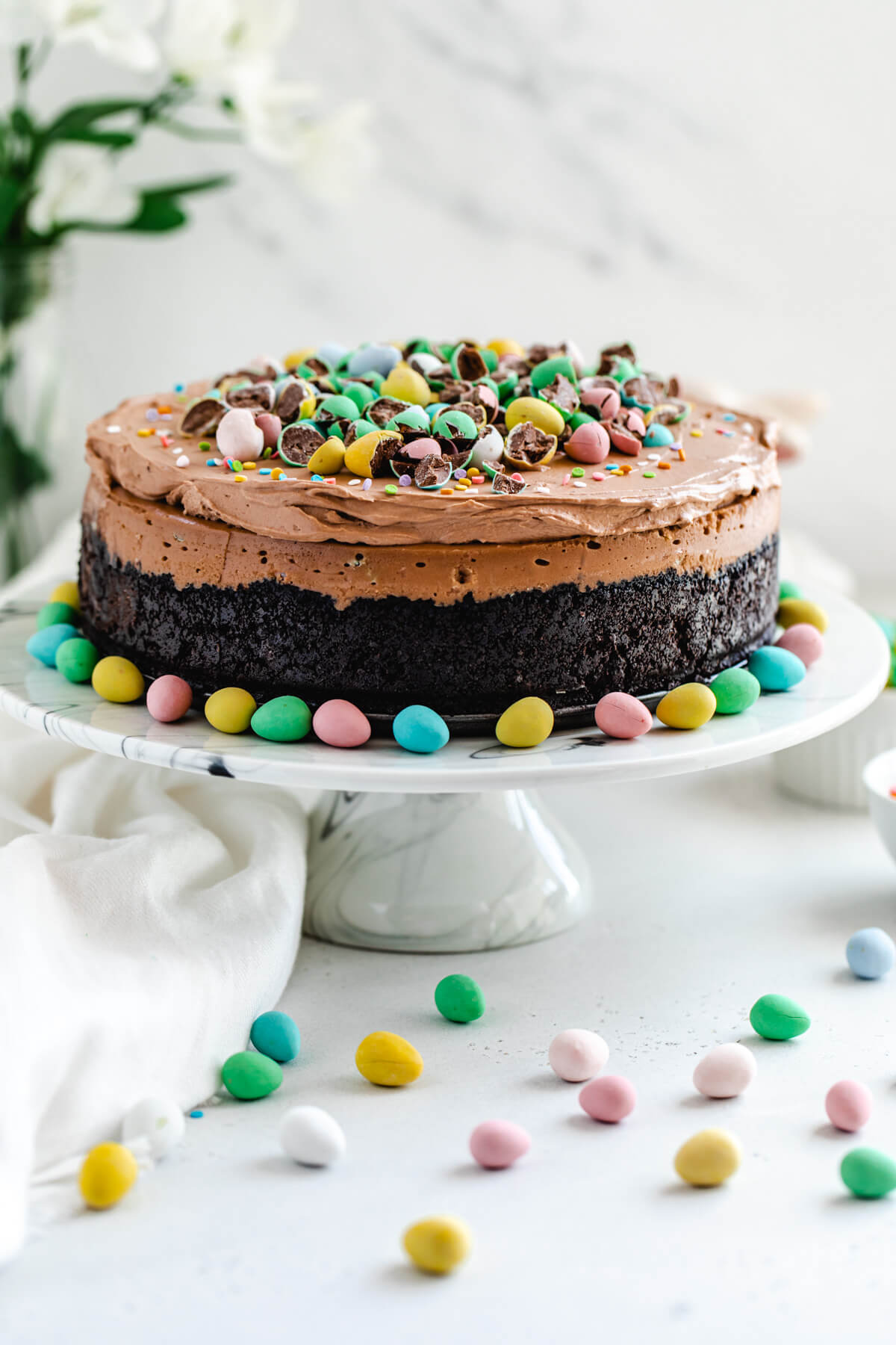 cheesecake on a marble cake stand with mini chocolate Easter eggs