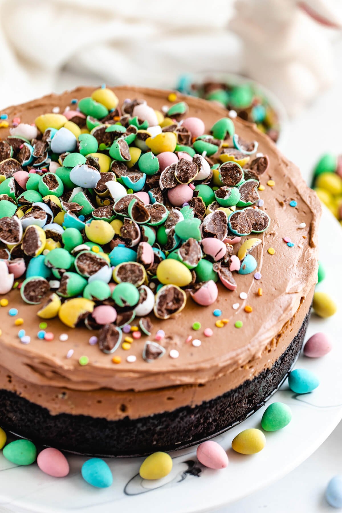 cheesecake on a cake stand surrounded by mini chocolate eggs