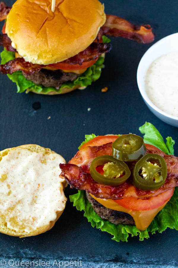 beer burgers with beer cheese sauce, fresh lettuce, tomatoes, crispy bacon, jalapeños and spicy aioli