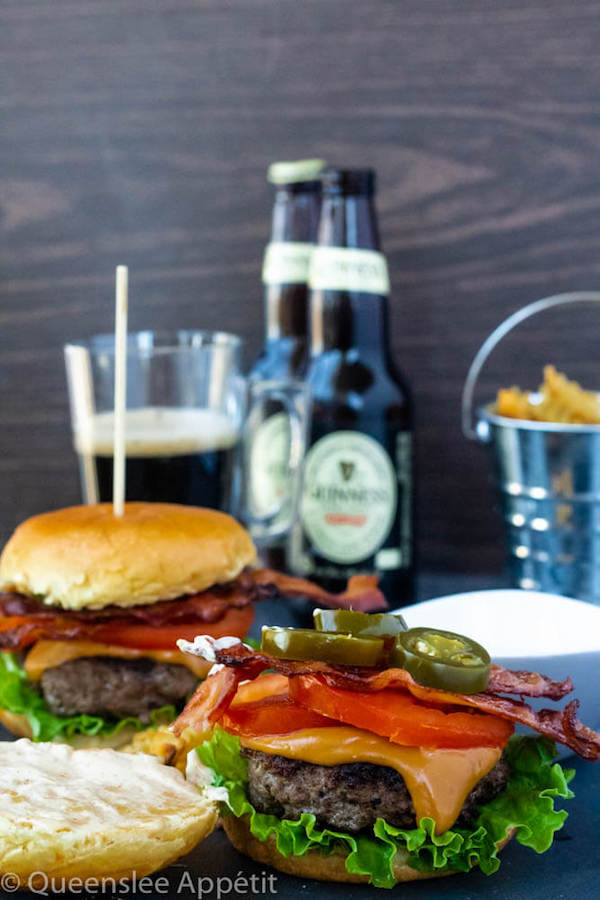 beer burgers with beer cheese sauce, fresh lettuce, tomatoes, crispy bacon, jalapeños and spicy aioli