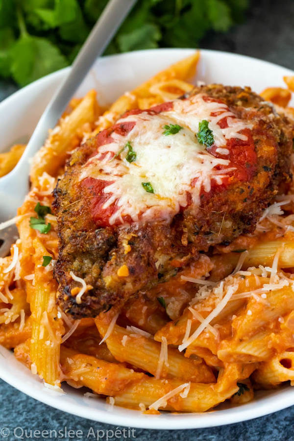 crispy chicken parmesan on a plate of penne alla vodka 