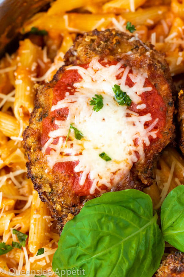 crispy chicken parmesan in a pot of penne alla vodka with basil leaf garnish