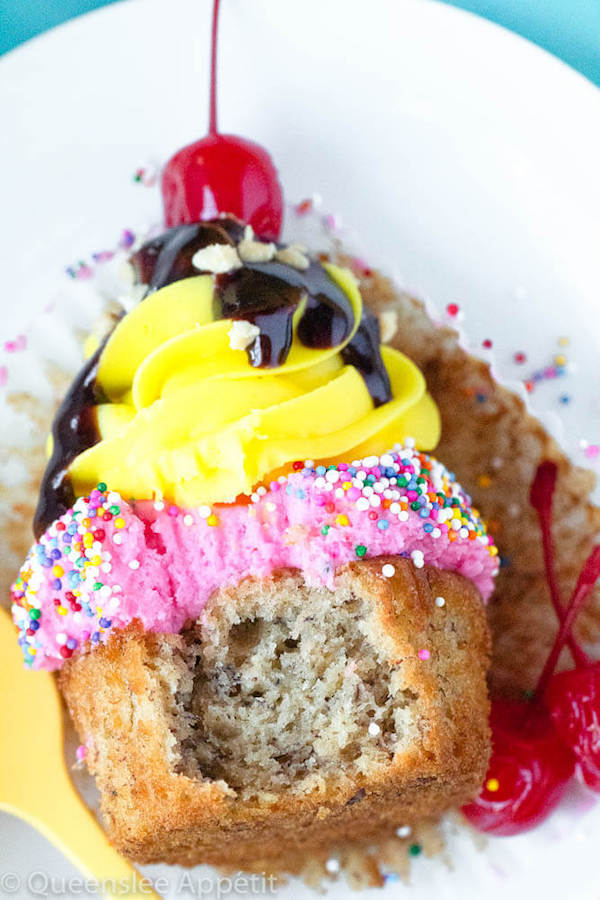 moist and delicious banana cupcake that’s been decorated with strawberry and vanilla buttercream, colourful sprinkles, chocolate sauce, chopped nuts and a bright red cherry on top