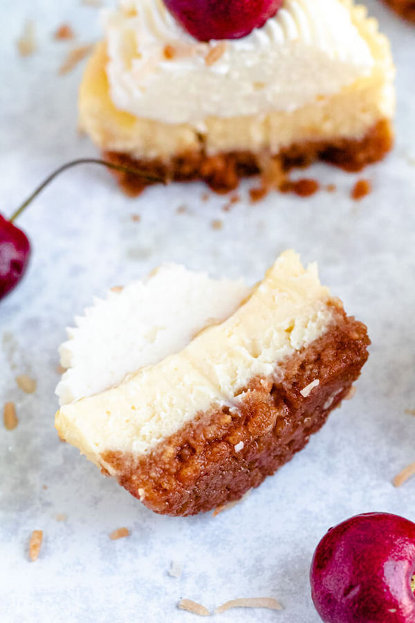 mini piña colada cheesecakes with pineapple sauce, coconut whipped cream, toasted coconut and a cherry on top.