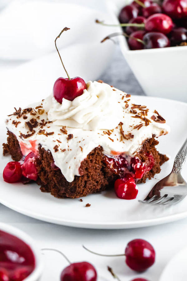 chocolate cake filled with cherry pie filling and topped with whipped cream, chocolate shavings and a cherry