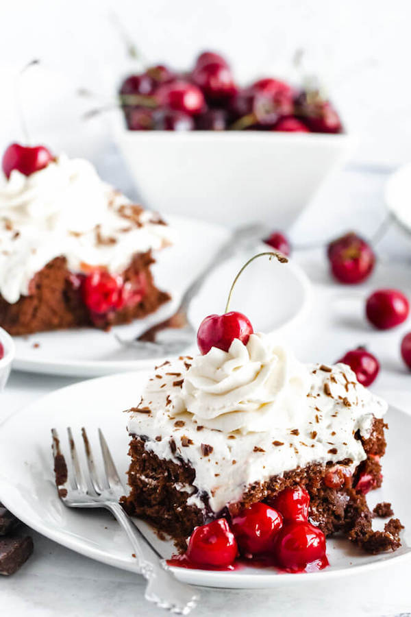 chocolate cake filled with cherry pie filling and topped with whipped cream, chocolate shavings and a cherry