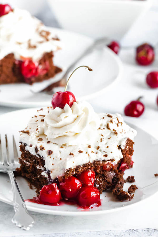 chocolate cake filled with cherry pie filling and topped with whipped cream, chocolate shavings and a cherry