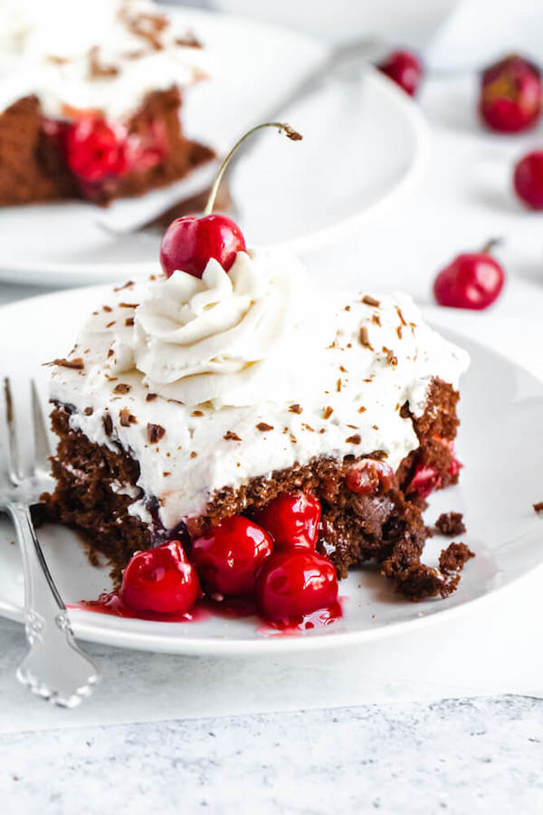 chocolate cake filled with cherry pie filling and topped with whipped cream, chocolate shavings and a cherry