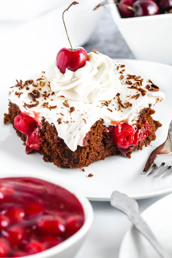 chocolate cake filled with cherry pie filling and topped with whipped cream, chocolate shavings and a cherry