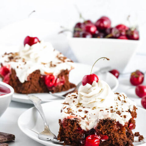 chocolate cake filled with cherry pie filling and topped with whipped cream, chocolate shavings and a cherry