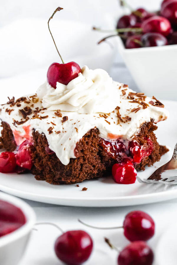 chocolate cake filled with cherry pie filling and topped with whipped cream, chocolate shavings and a cherry