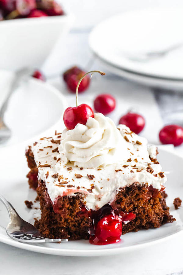 chocolate cake filled with cherry pie filling and topped with whipped cream, chocolate shavings and a cherry