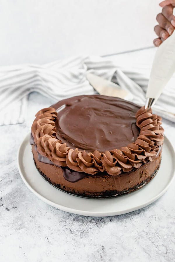 piping chocolate whipped cream rope border onto chocolate cheesecake