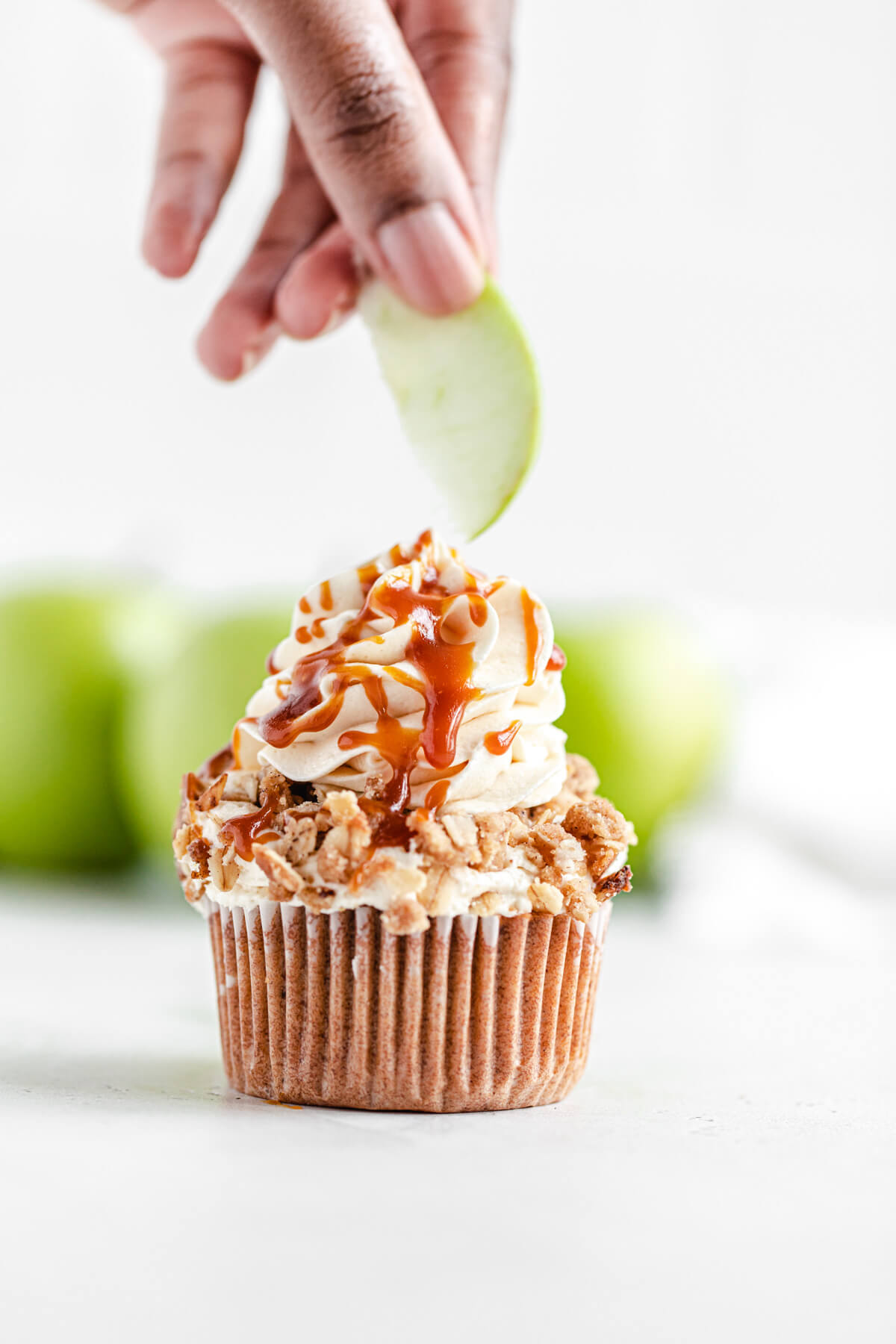 placing apple slice onto frosted cupcake
