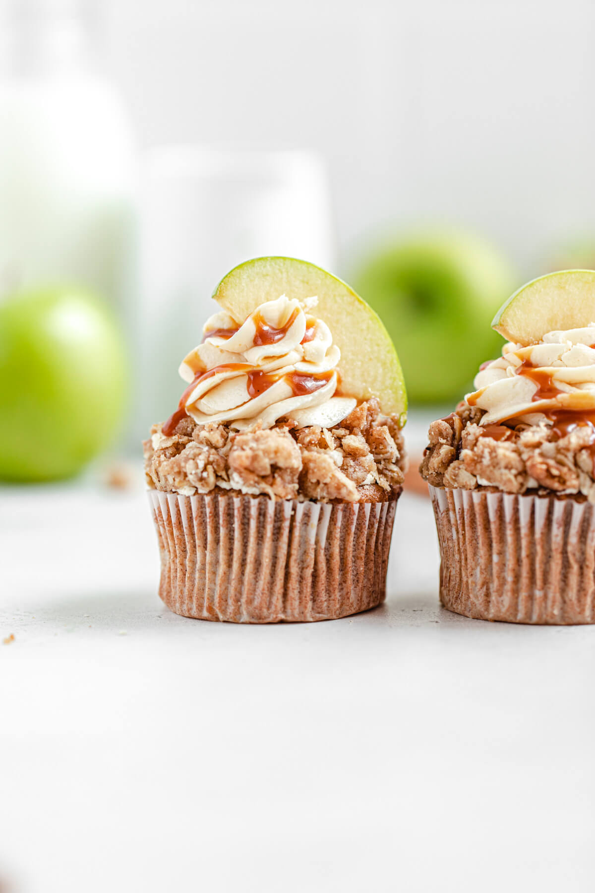 two cupcakes side by side with green apples in the background