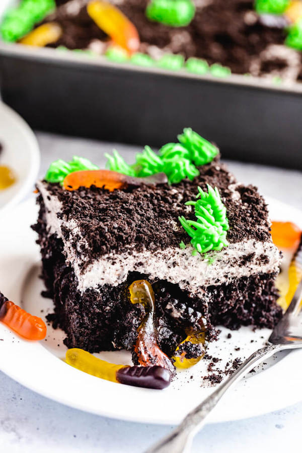 dark chocolate cake filled with chocolate pudding, Oreo crumbs, gummy worms and topped with Oreo cream cheese frosting, green grass buttercream and more Oreo crumbs and gummy worms