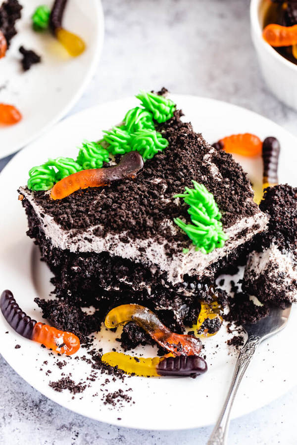 dark chocolate cake filled with chocolate pudding, Oreo crumbs, gummy worms and topped with Oreo cream cheese frosting, green grass buttercream and more Oreo crumbs and gummy worms