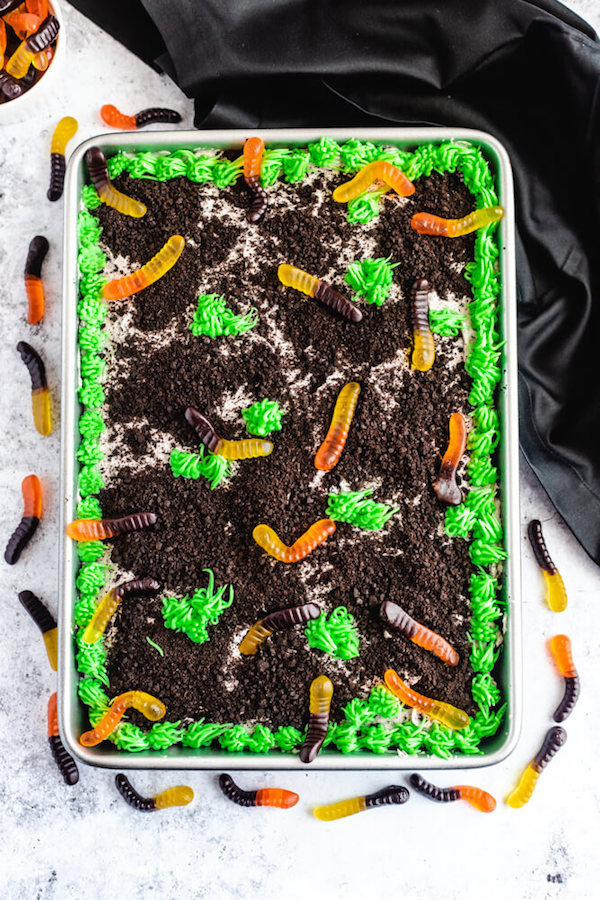 dark chocolate cake filled with chocolate pudding, Oreo crumbs, gummy worms and topped with Oreo cream cheese frosting, green grass buttercream and more Oreo crumbs and gummy worms