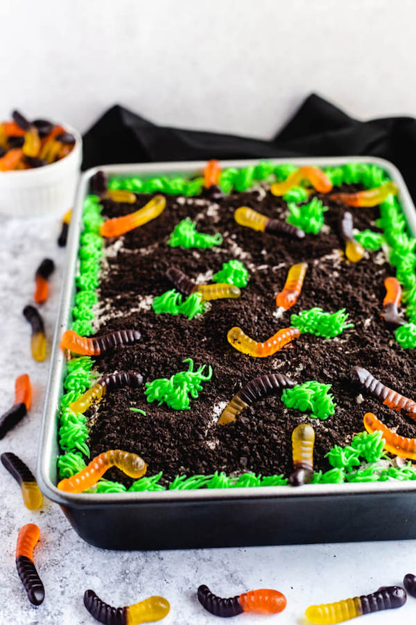 dark chocolate cake filled with chocolate pudding, Oreo crumbs, gummy worms and topped with Oreo cream cheese frosting, green grass buttercream and more Oreo crumbs and gummy worms