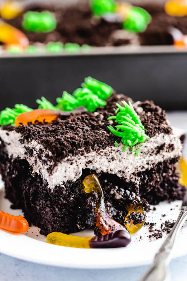 dark chocolate cake filled with chocolate pudding, Oreo crumbs, gummy worms and topped with Oreo cream cheese frosting, green grass buttercream and more Oreo crumbs and gummy worms