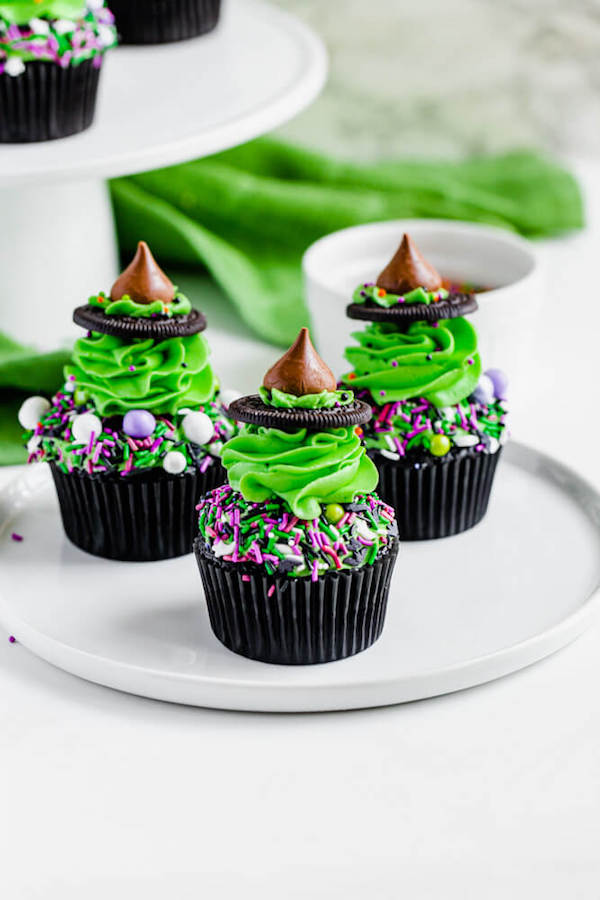 black chocolate cupcakes topped with green buttercream and witch hats