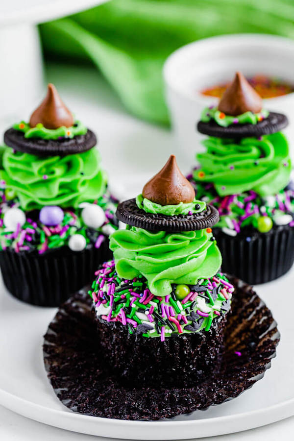black chocolate cupcakes topped with green buttercream and witch hats