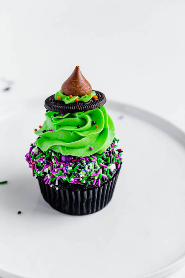 black chocolate cupcakes topped with green buttercream and witch hats